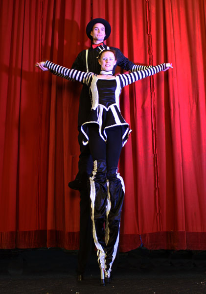 stilt walkers performing next to the red curtain in newcastle, australia